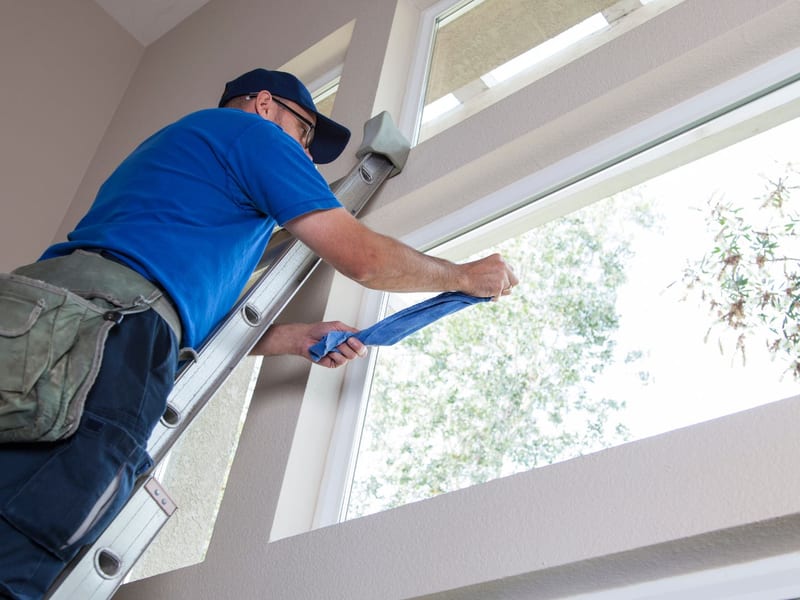 Window cleaner squeegeeing the interior of a tall residential window