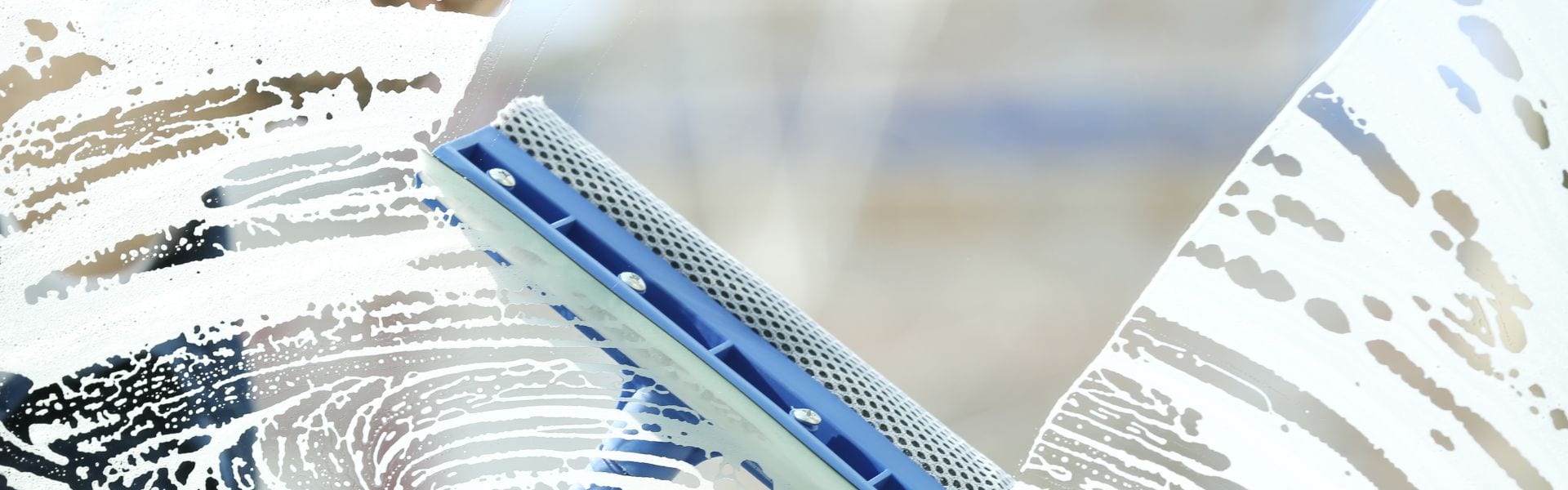 Squeegee removing soap and water from glass during a deep clean